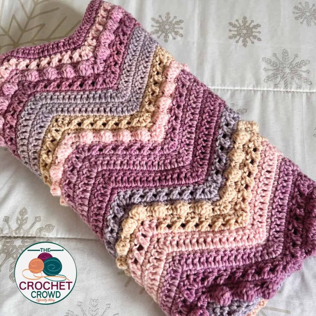 The beautiful Hugs & Kisses Wave Blanket was crocheted with Caron Baby Cakes yarn. The free downloadable pattern is available at The Crochet Crowd. The pattern includes the stitch multiple so you can make your blanket in the size you want. Watch the video tutorial on YouTube here.