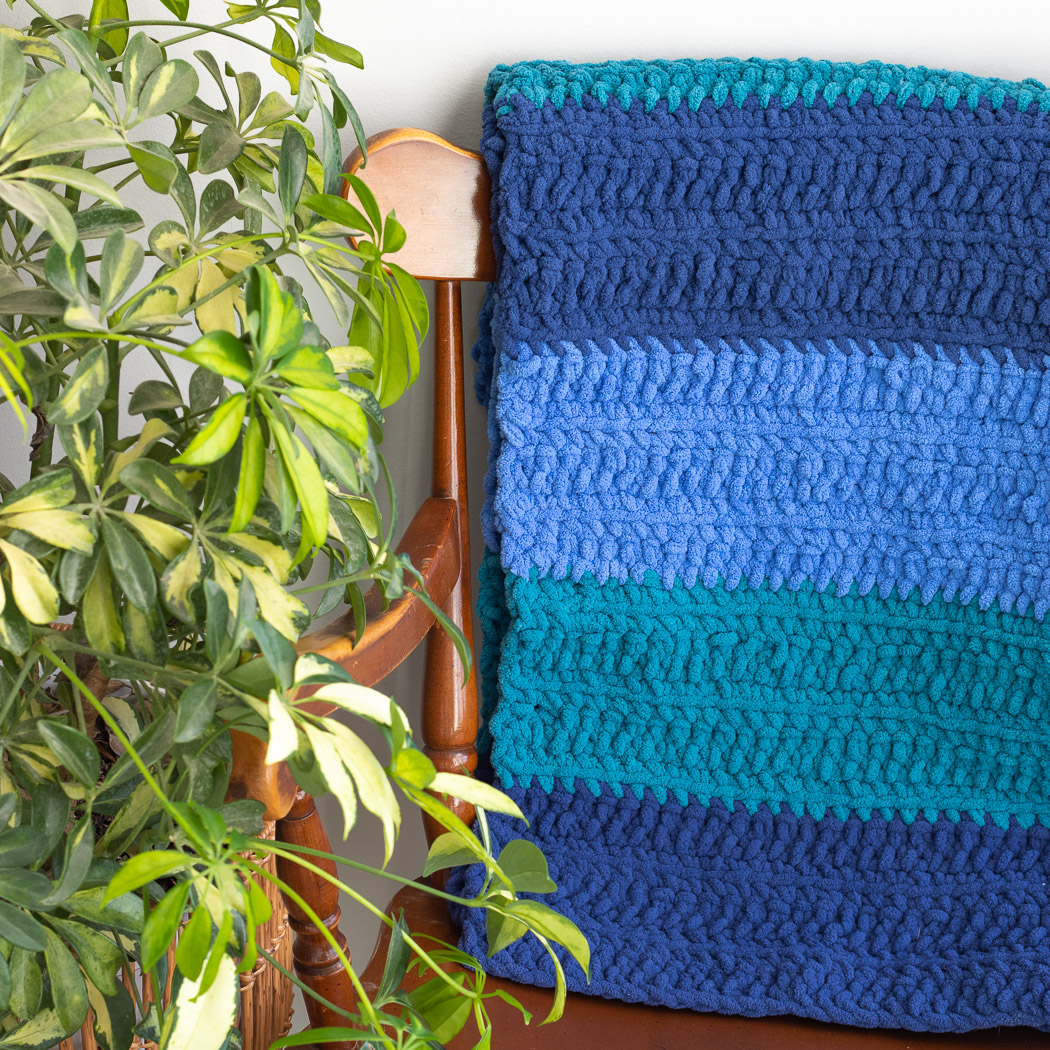 The Henry Blanket is an easy, chunky baby blanket crochet pattern made with Bernat Blanket O'Go, or three colors of super bulky blanket yarn.