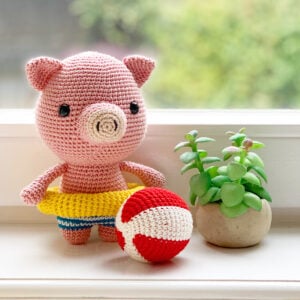 Crochet this adorable pig with a swim ring and beach ball! Billie the Pig is a soft and squishy summer amigurumi toy made with sport weight cotton yarn. Perfect for stash-busting and gift-giving!